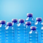 Group of blue plastic bottles symbolizing recycling and zero waste on a gradient background.